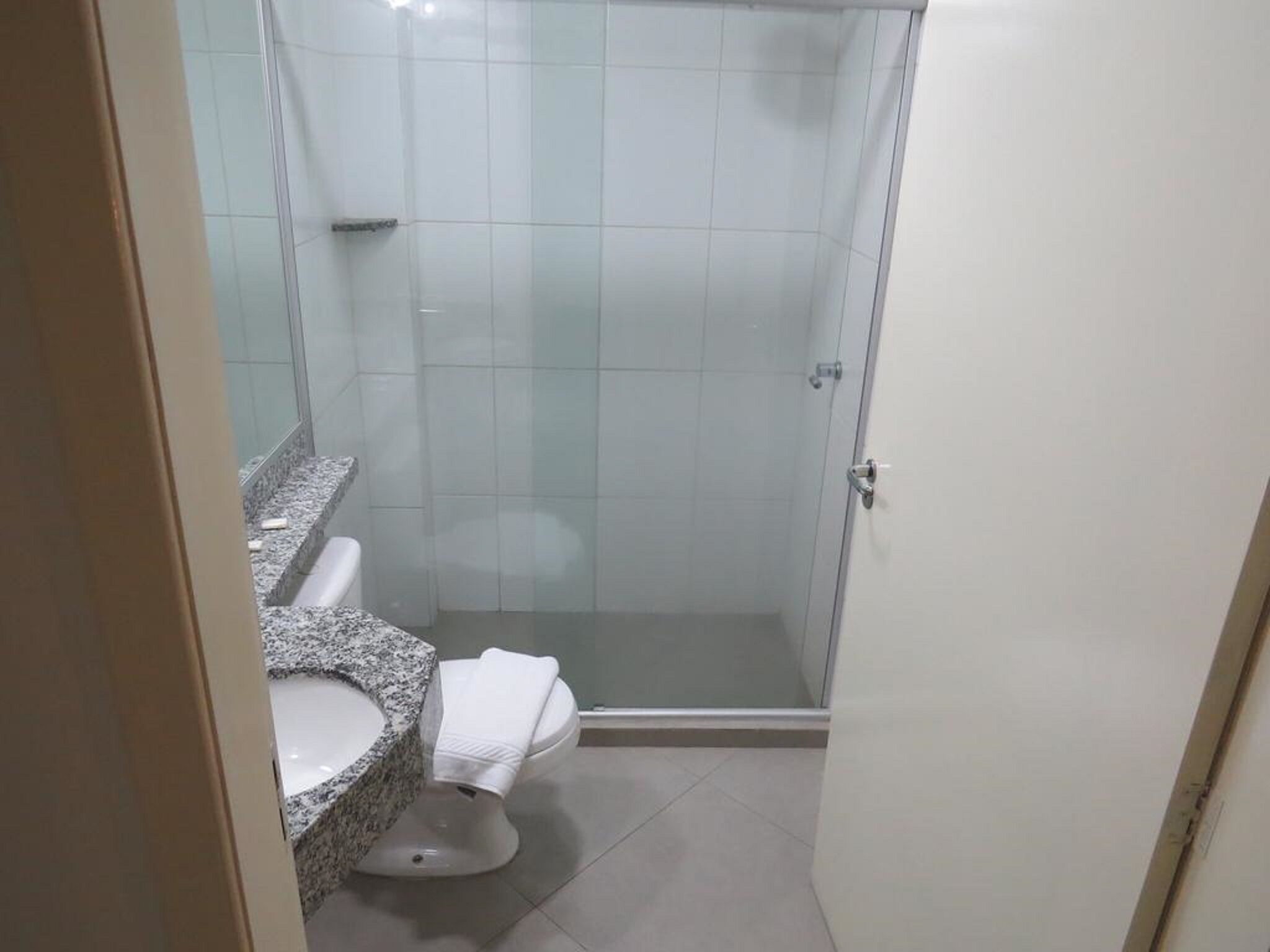 Une salle de bain avec douche, toilettes et lavabo avec un plan de travail en granit.