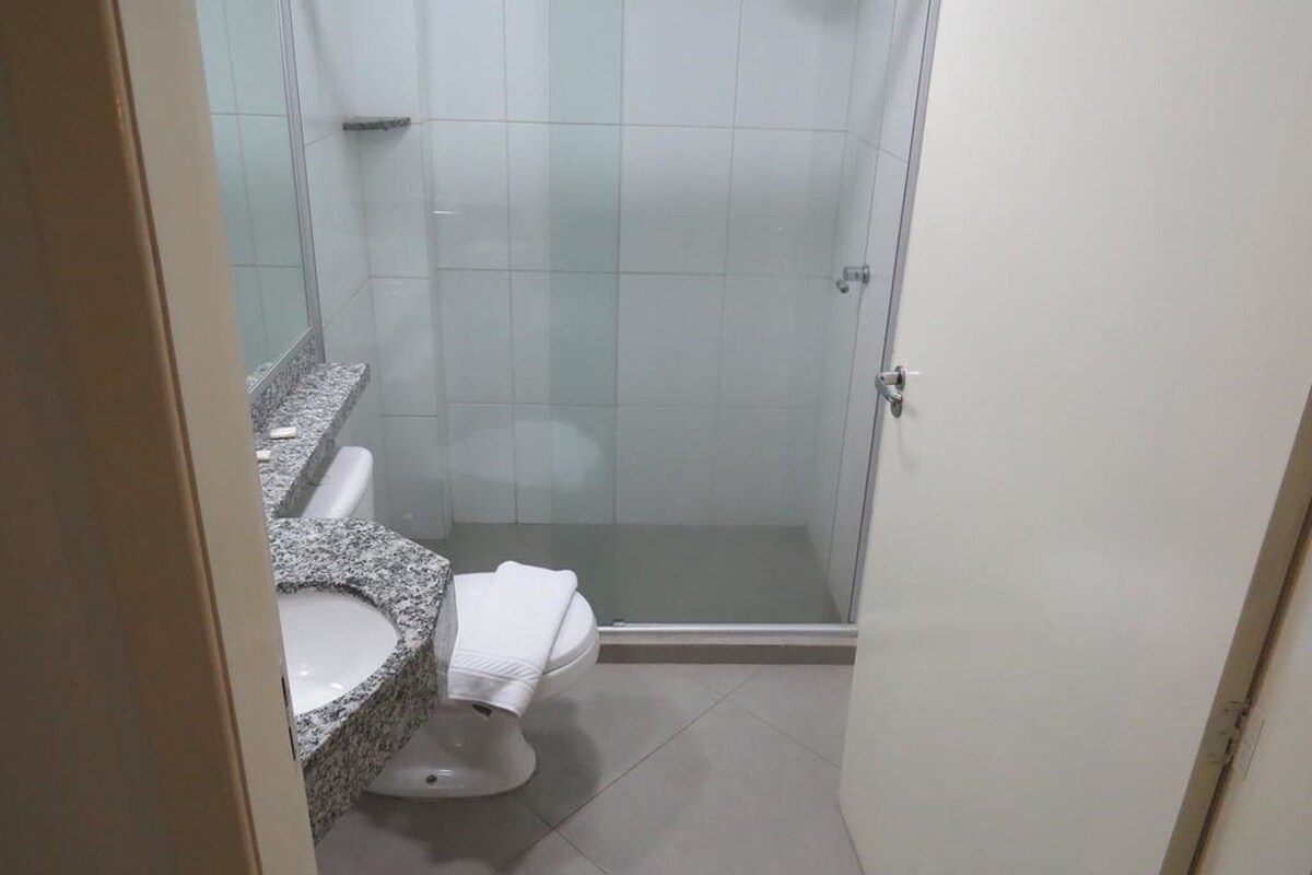 Un baño con ducha, inodoro e lavamanos de encimera de granito.