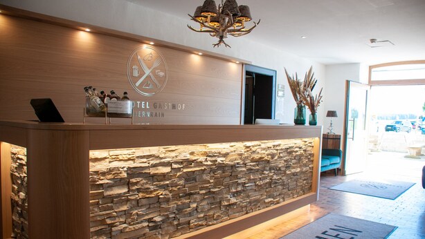 Een hotel receptiebalie met een stenen muur en een houten toonbank.