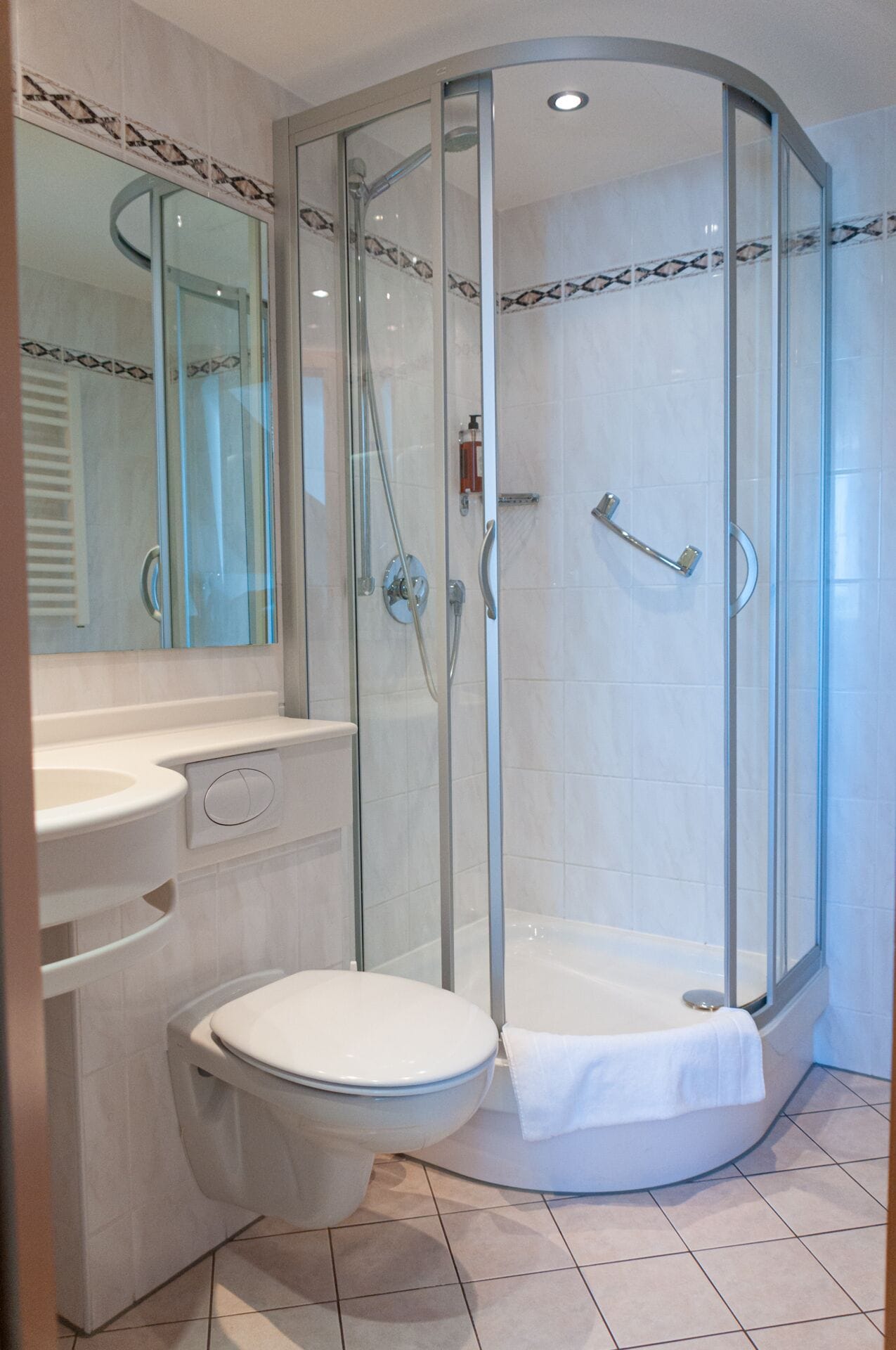 Un baño moderno con cabina de ducha de vidrio, inodoro y lavabo.