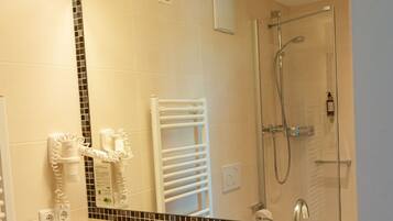 A bathroom with a sink, mirror, and shower.