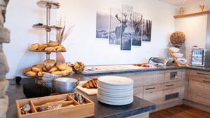 Een moderne keuken met een buffetopstelling, inclusief diverse broden en gebak, een fruitschaal en een spoelbak.