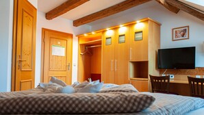 Een slaapkamer met een bed, een houten garderobe en een bureau met een stoel.