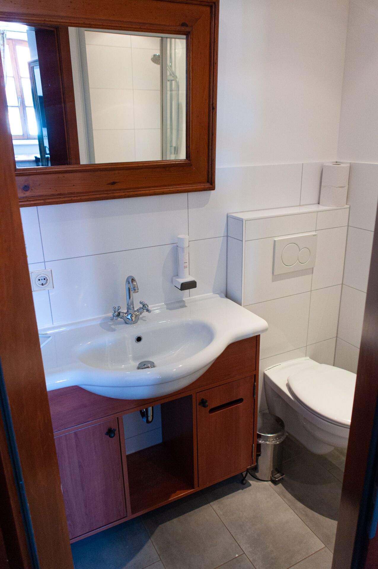 Een badkamer met een wit wastafel, een houten kastje en een toilet.
