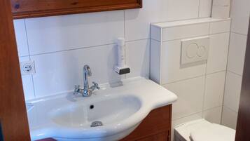 A bathroom with a white sink, wooden cabinet, and a toilet.