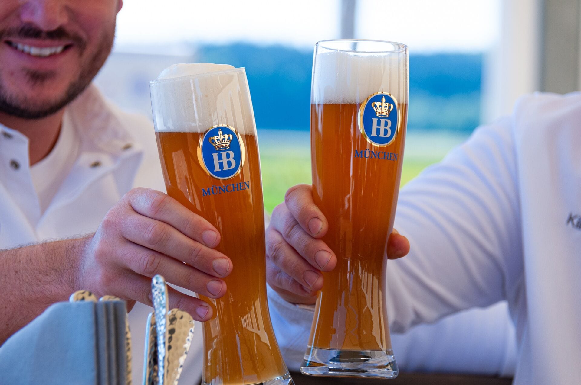Dos vasos de cerveza con logotipos, sostenidos por una persona.