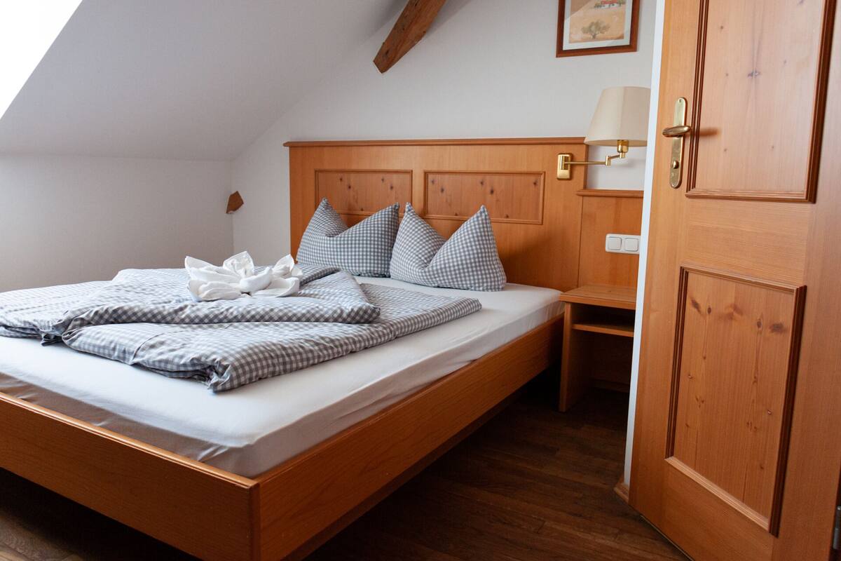 Un lit bien fait, avec une literie à carreaux, une tête de lit en bois, une table de chevet avec une lampe et une armoire.