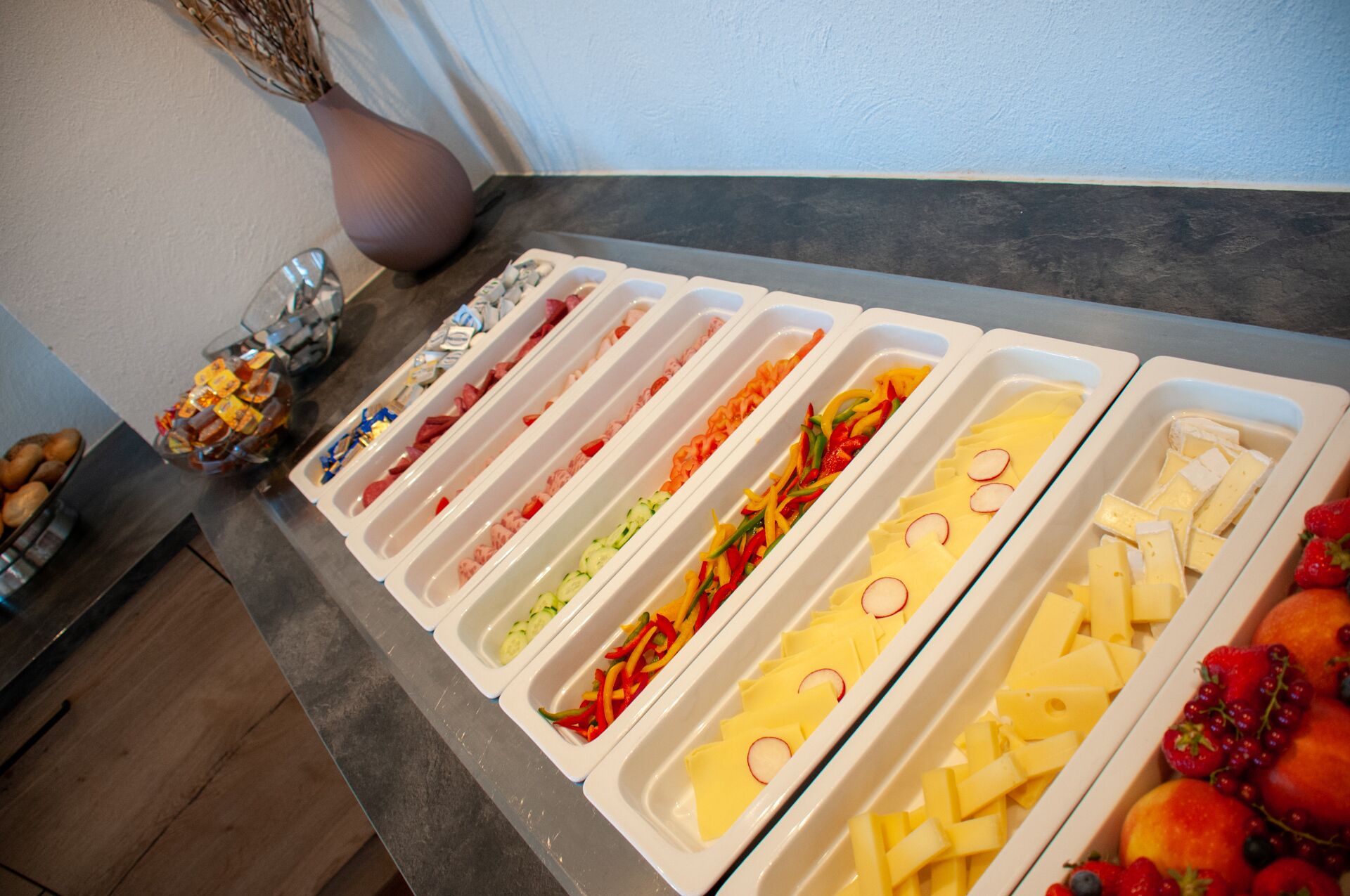 A buffet with various food items including fruits, cheeses, and vegetables.