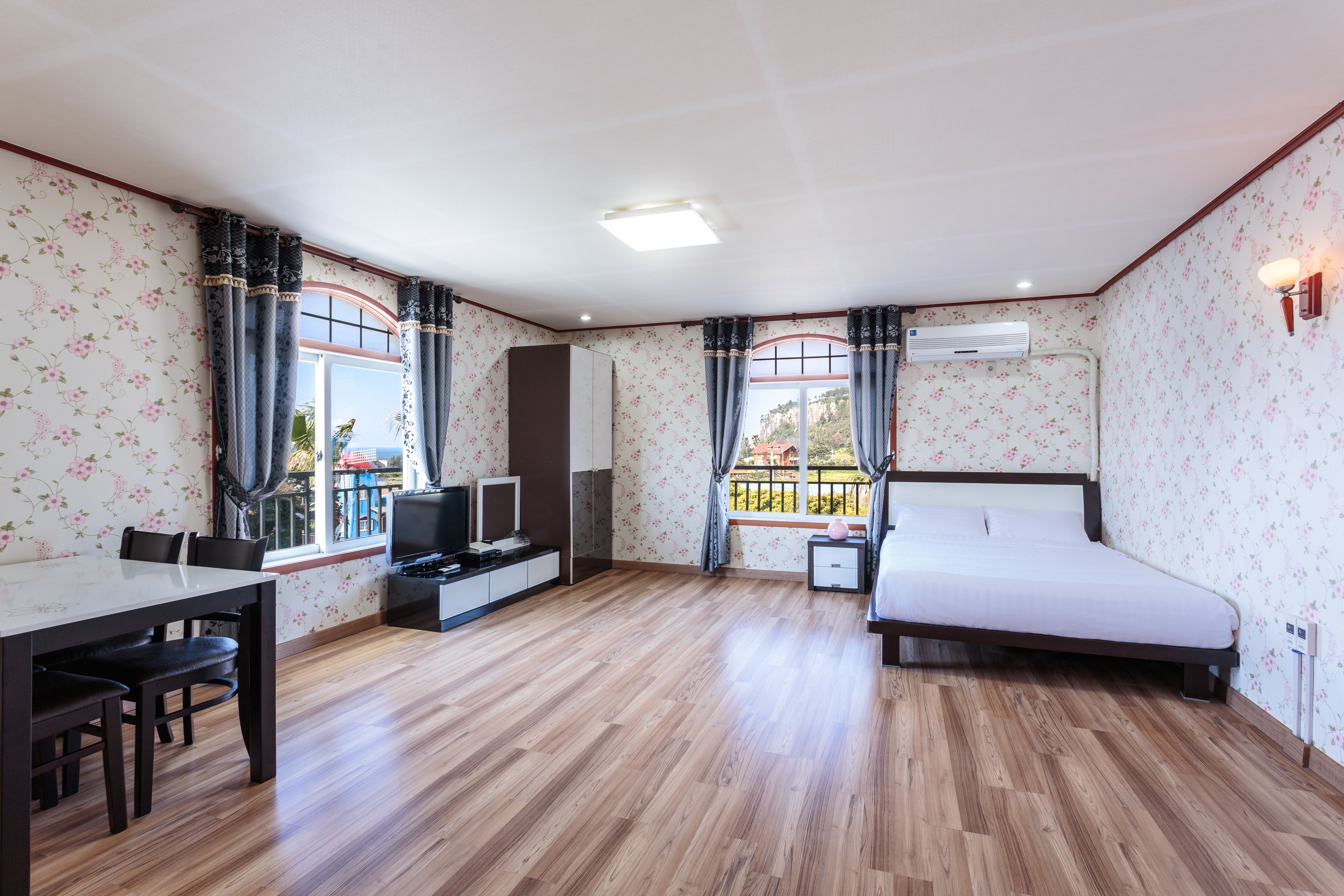Une chambre d’hôtel avec un lit, un bureau, une télévision et une fenêtre avec des rideaux.