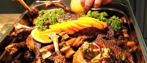 A person serving a large platter of roasted meats and vegetables.