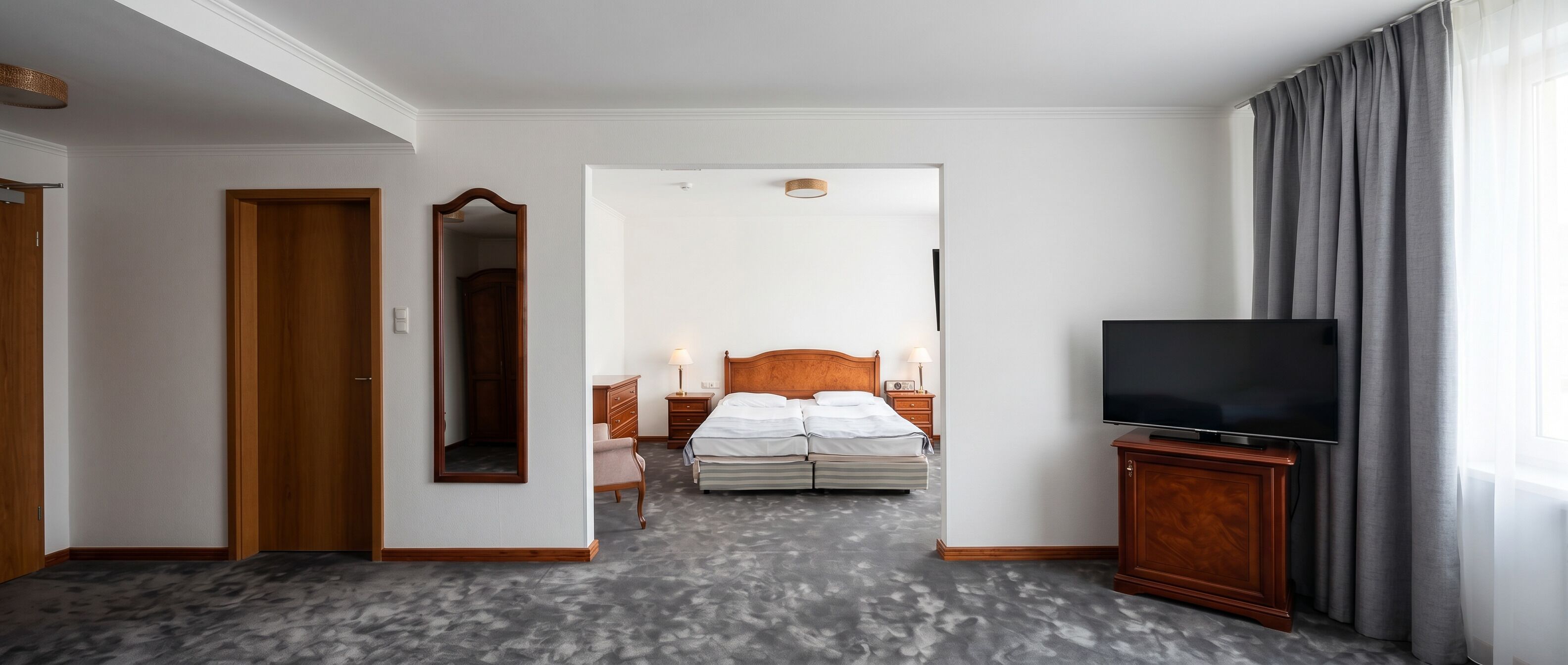 Een hotelkamer met een bed, een televisie, een spiegel, een dressoir en een deur.