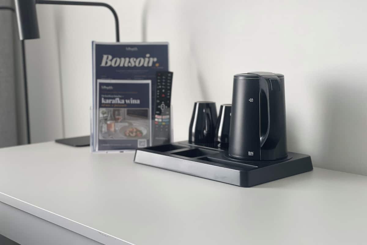 Une machine à café, une télécommande et un magazine sur une table blanche.