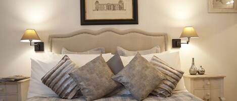 A neatly made bed with a headboard, two bedside lamps, and a framed picture on the wall.