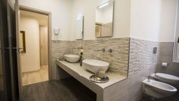Une salle de bain moderne avec deux lavabos, un bidet et des toilettes.