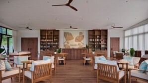 A spacious living area with wooden furniture, a central bookshelf, and ceiling fans. - Samanea Beach Resort & Spa (Kep)