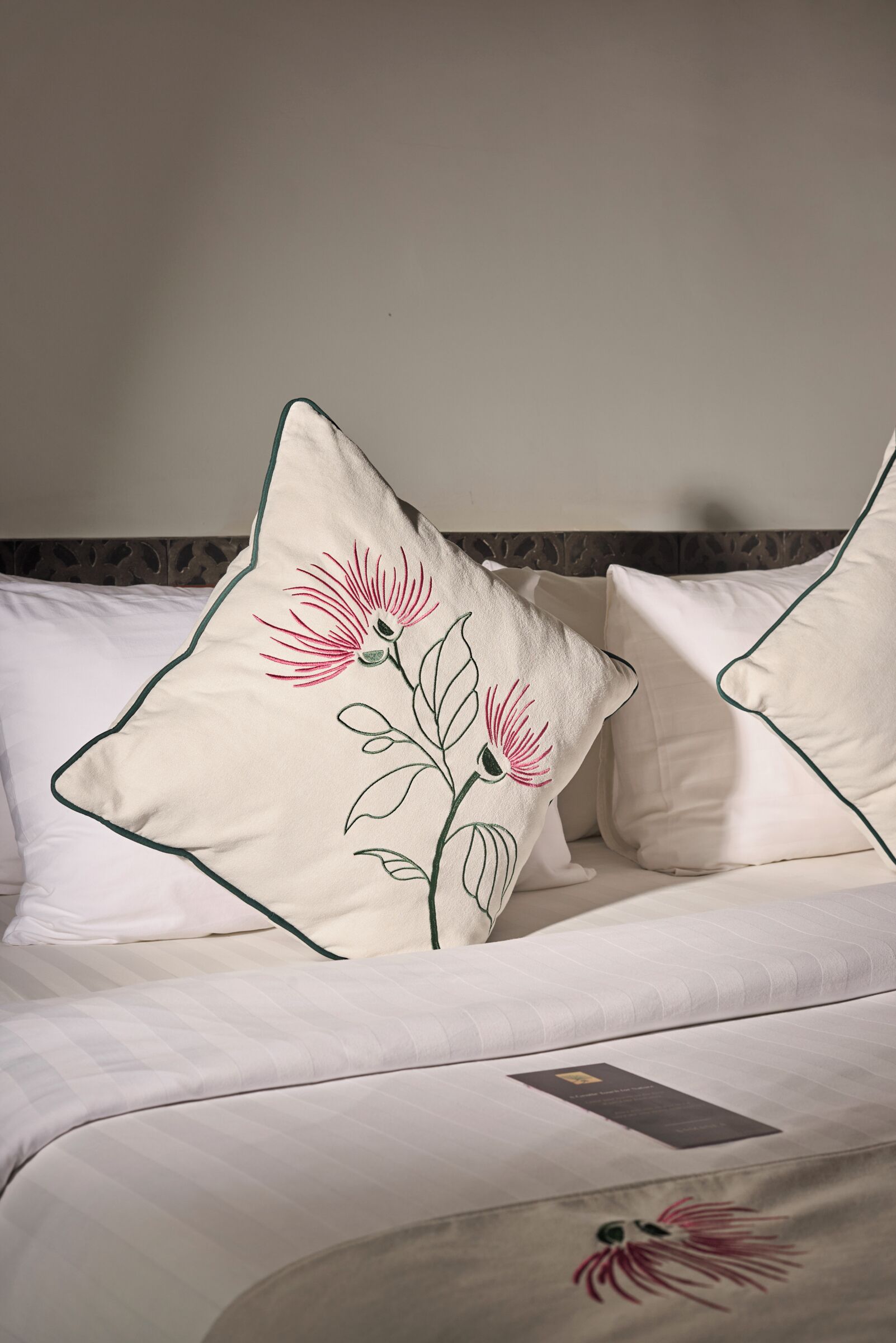 A bed with white bedding and pillows featuring embroidered flowers.