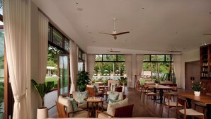 A spacious indoor area with large windows, a pool view, and a variety of seating arrangements. - Samanea Beach Resort & Spa (Kep)