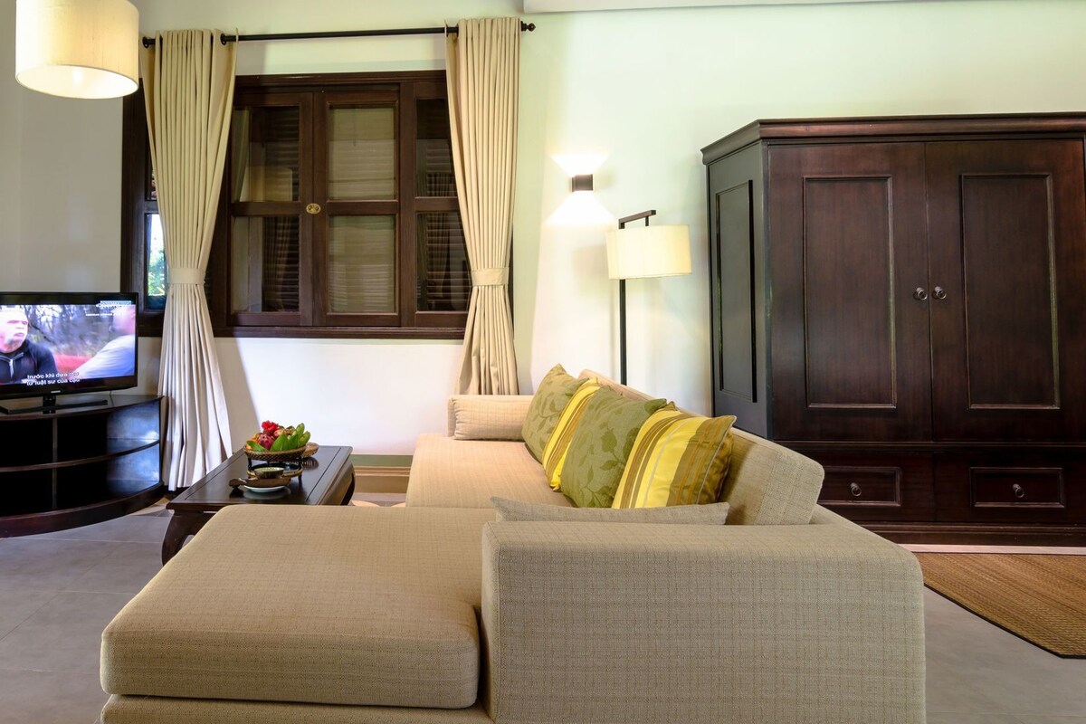 A living room with a sofa, a television, a cabinet, and curtains.
