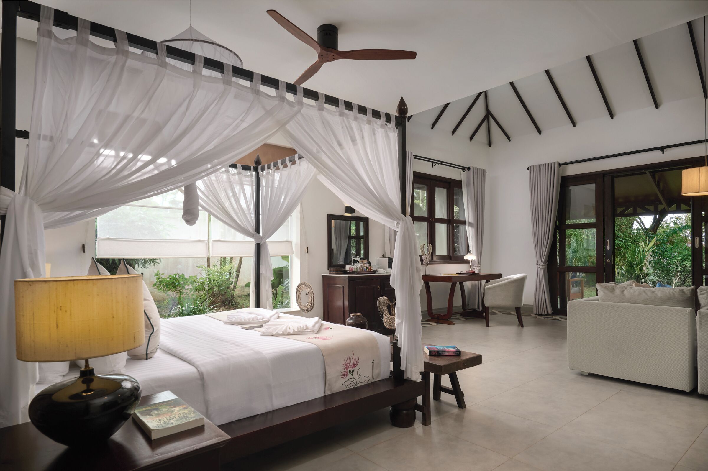 A bedroom with a canopy bed, a desk, a chair, and a sofa.