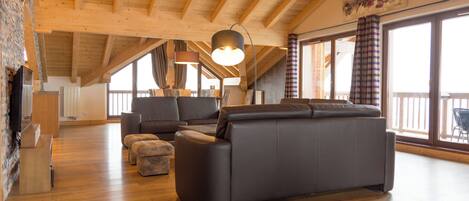 A spacious living area with a wooden ceiling, a sofa, a coffee table, and a fireplace.