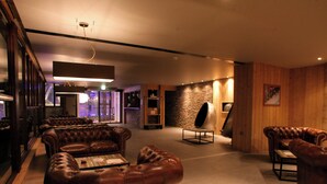 A spacious living area with leather sofas, a coffee table, and a stone accent wall. - Résidence Koh-I Nor by Les Etincelles (Les Belleville)