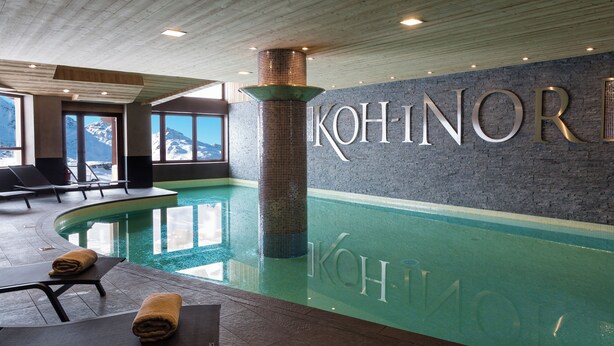 A modern indoor swimming pool with lounge chairs and a view of mountains through large windows. - Résidence Koh-I Nor by Les Etincelles (Les Belleville)