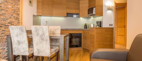Una cocina compacta con armarios de madera, horno empotrado y un comedor con mesa y sillas.