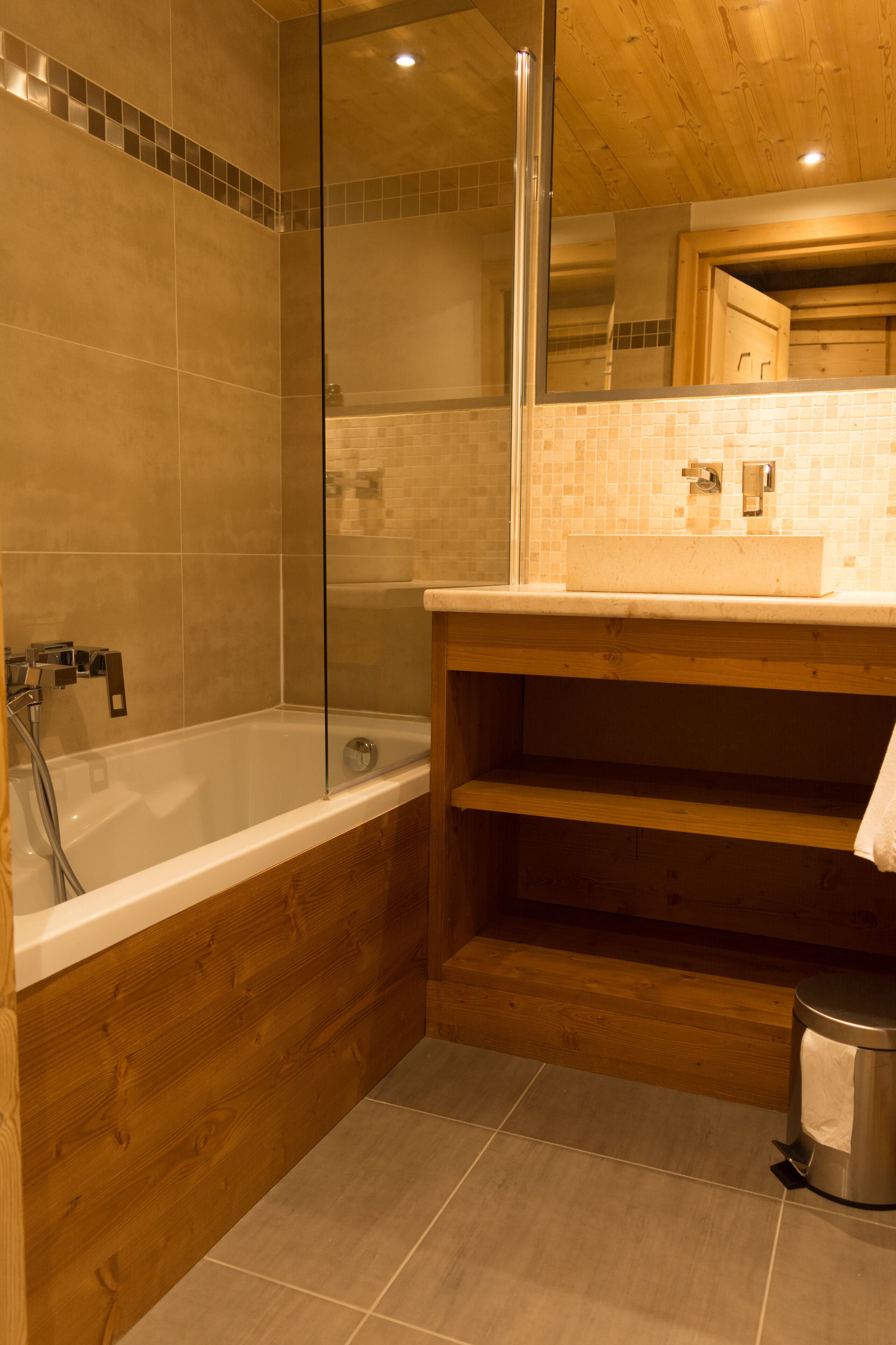 A bathroom with a glass shower enclosure, a wooden vanity, and a bathtub.