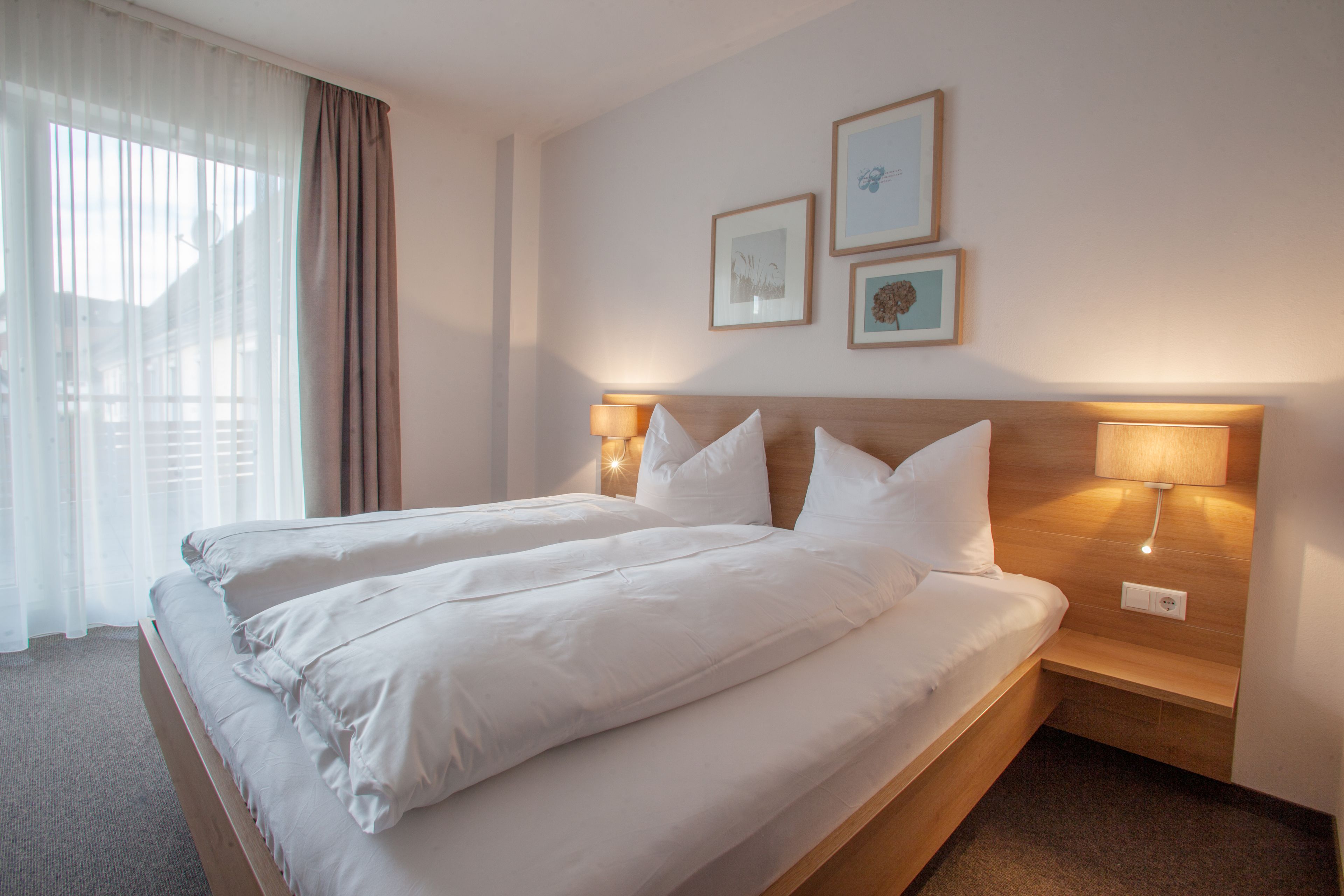 A double bed with white linens, two bedside lamps, and a headboard.