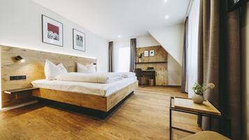 A modern bedroom with a wooden bed, a desk, and a small seating area.