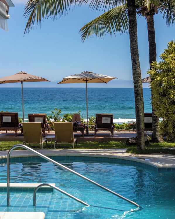 A poolside area with lounge chairs and umbrellas, overlooking the ocean. - Amora Hotel (São Sebastião)