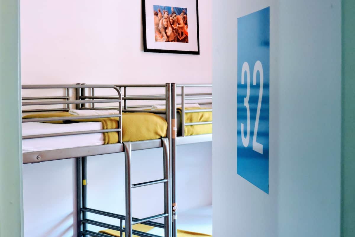 A bunk bed room with a framed picture on the wall and a blue sign with the number 32.