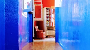 A narrow hallway with wooden flooring, a red door, and a blue wall. - Home Backpackers Valencia by Feetup Hostels (Valencia)