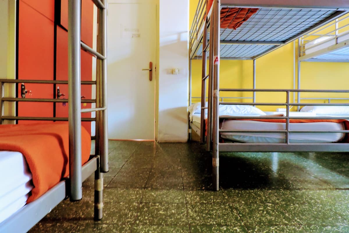 A dormitory room with bunk beds, a door, and a tiled floor.