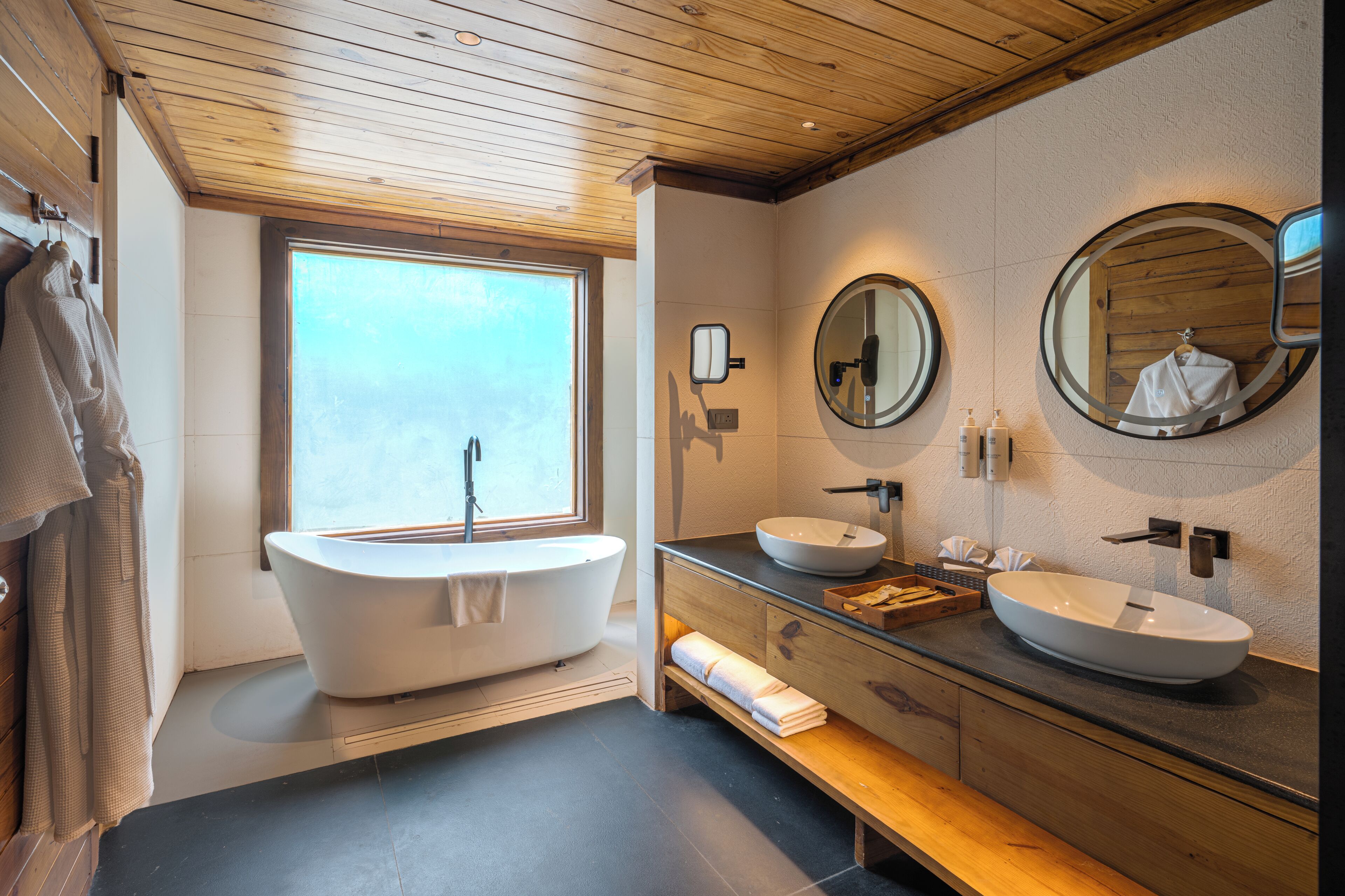 A modern bathroom with a freestanding bathtub, two sinks, and a large mirror.