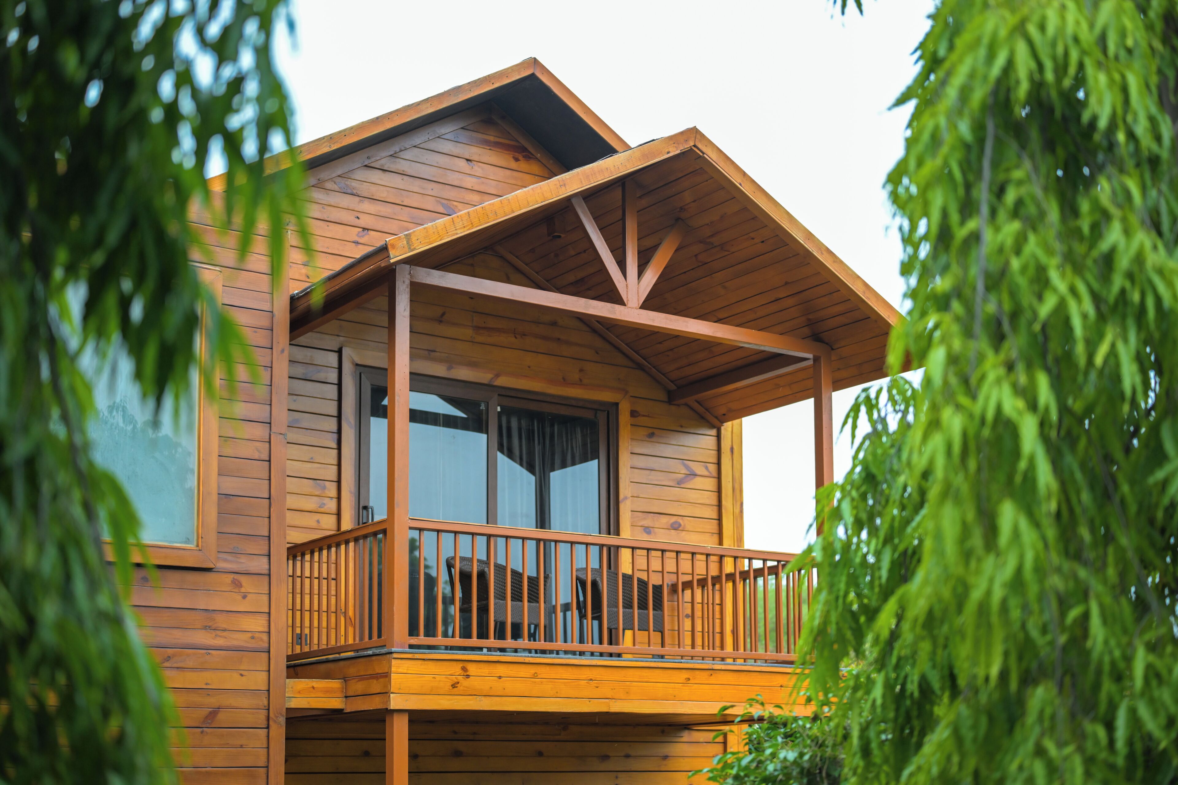 A wooden cabin with a balcony, large windows, and a visible door.