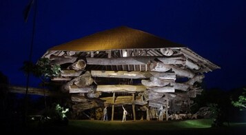 Un edificio grande y de diseño único con tejado de paja y estructura de troncos apilados.