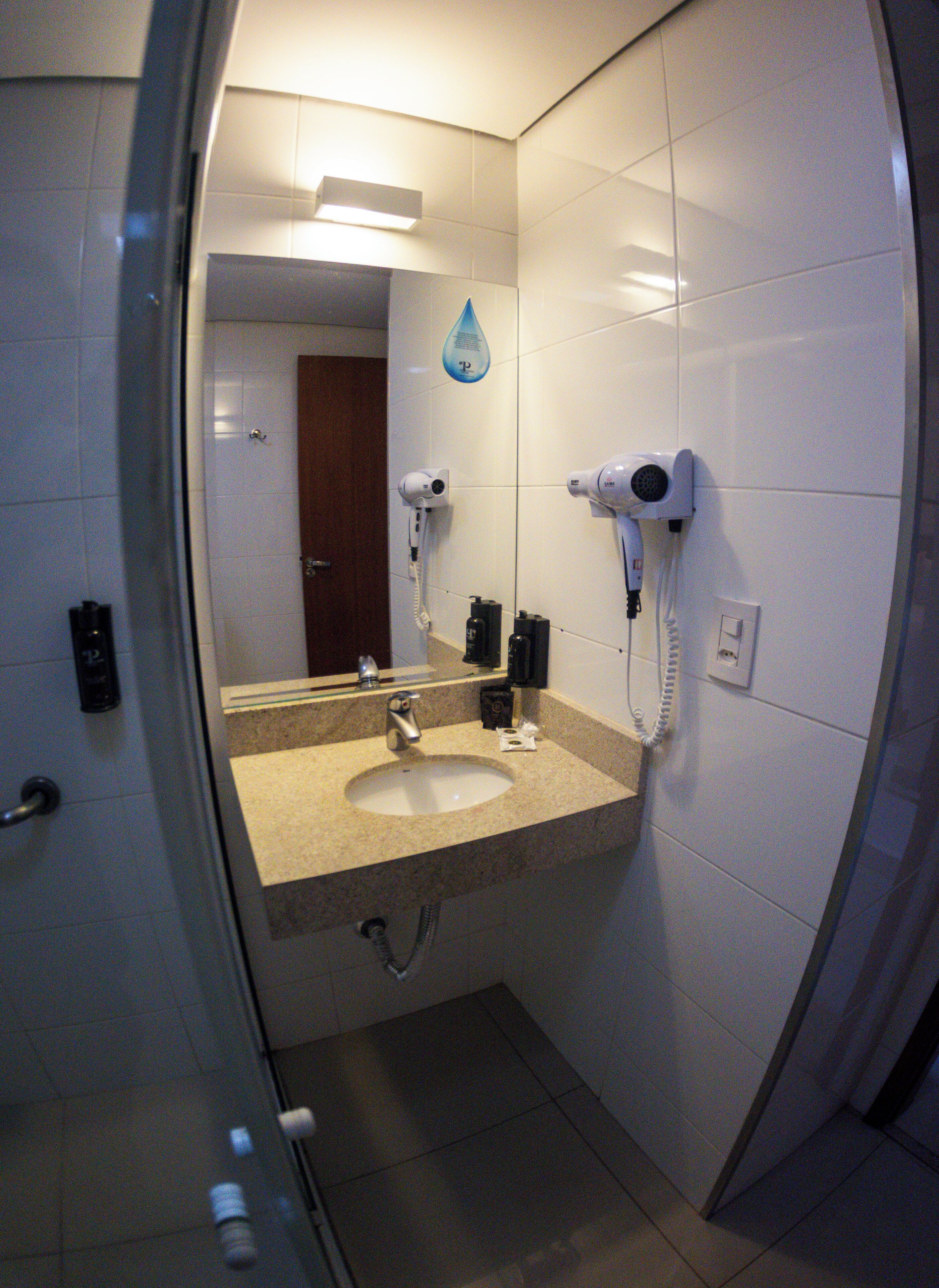 A bathroom with a sink, two hair dryers, and a mirror.