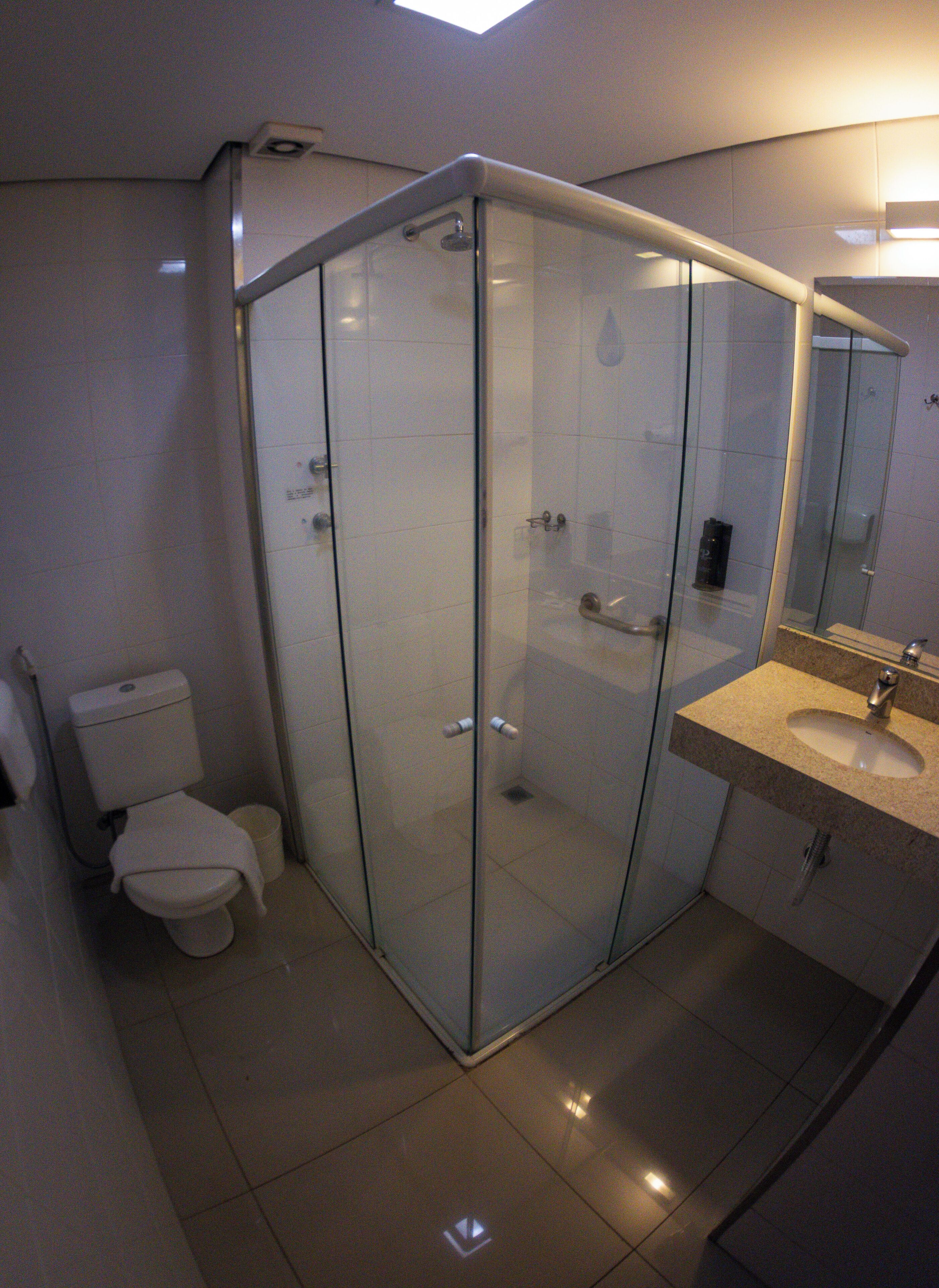Un baño moderno con cabina de ducha de vidrio, inodoro y lavamanos con espejo.