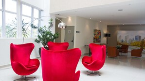 Een moderne lobby met heldere verlichting, een groot raam en rode stoelen.
