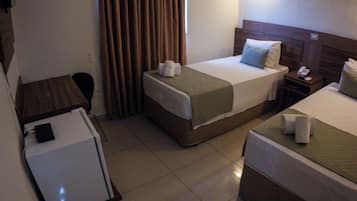 A hotel room with two beds, a desk, a chair, a small table, and an air conditioning unit.