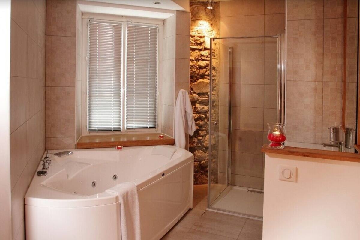 Een moderne badkamer met een groot bad, een douche met glazen wand en een accentmuur van steen.