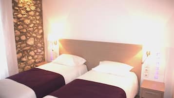A hotel room with two beds, a stone wall, and a wooden headboard.