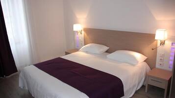 A hotel room with a bed, two bedside tables, and a nightstand.