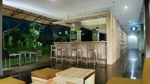 A modern bar area with wooden furniture and a view of greenery outside. - Hotel Neo Denpasar by ASTON (Denpasar)