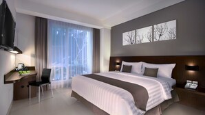 A modern hotel room with a large bed, a desk with a chair, a flat-screen TV, and a large window with curtains. - Hotel Neo Denpasar by ASTON (Denpasar)