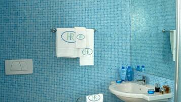 Une salle de bain avec des carreaux de mosaïque bleus, des toilettes, un bidet, un lavabo et un miroir.