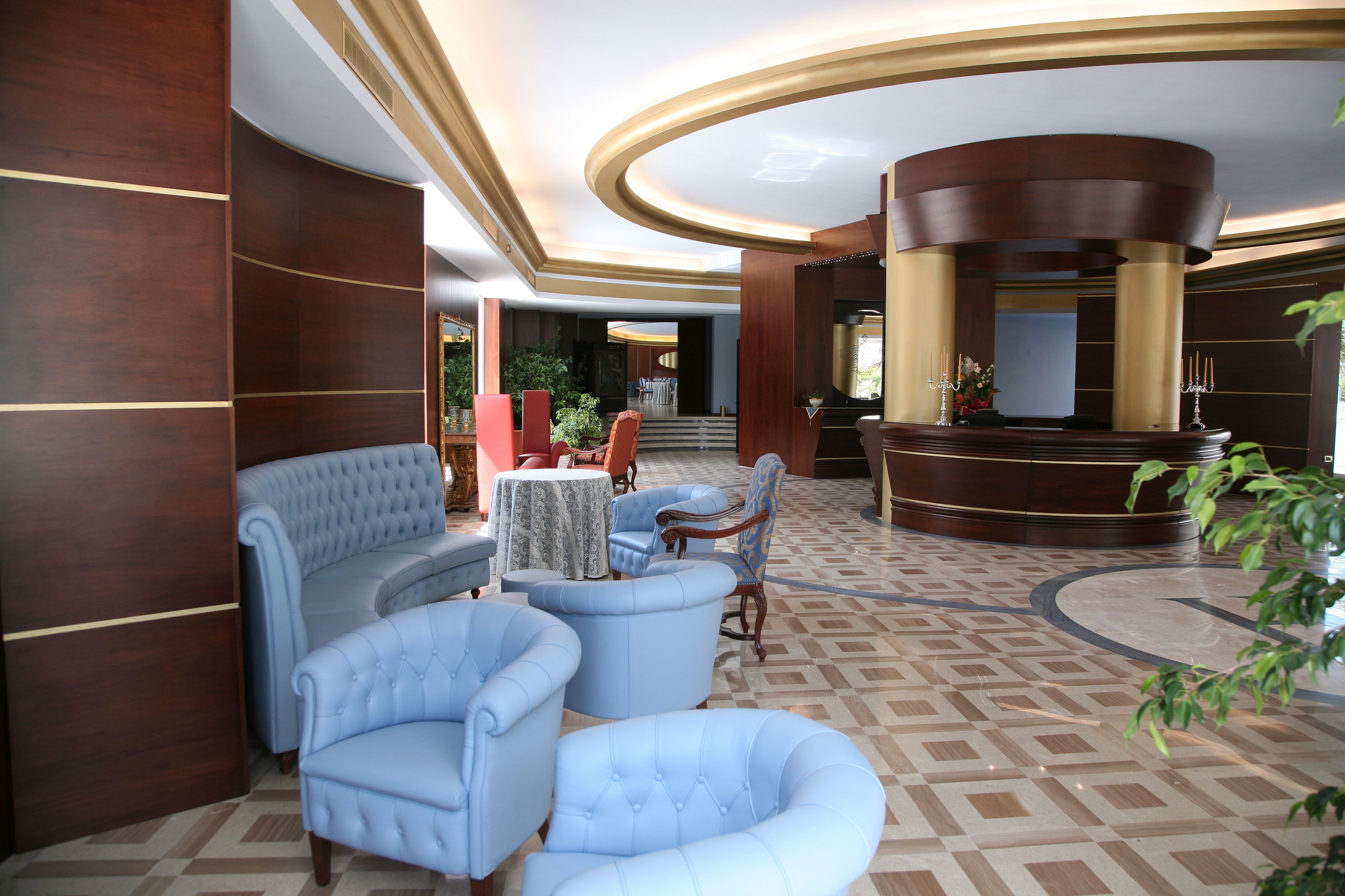 Una hall con pavimento a scacchi, una reception e zone salotto.