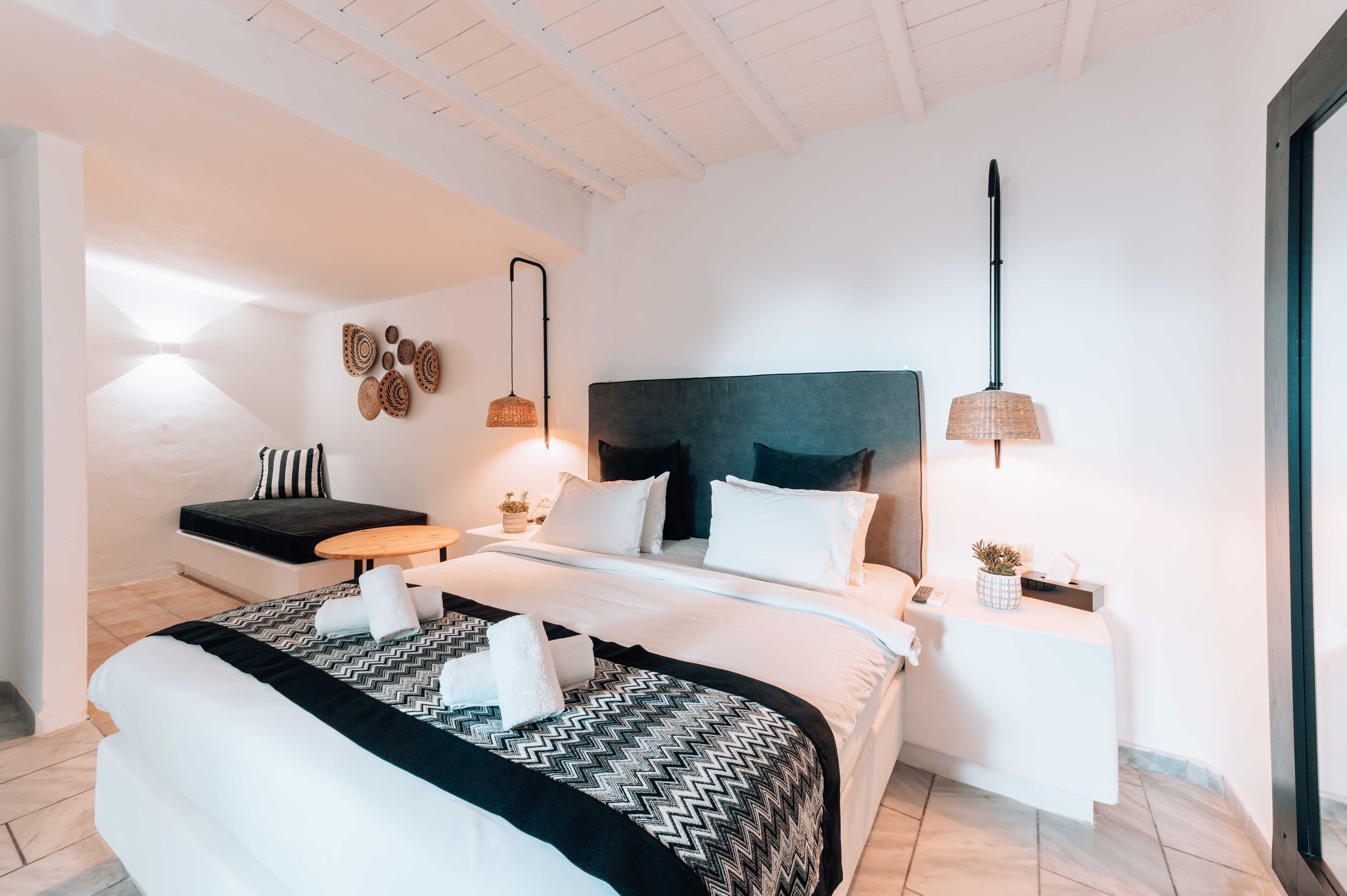 Une chambre à coucher moderne avec un grand lit, des tables de chevet, une tête de lit et des lampes fixées au mur.