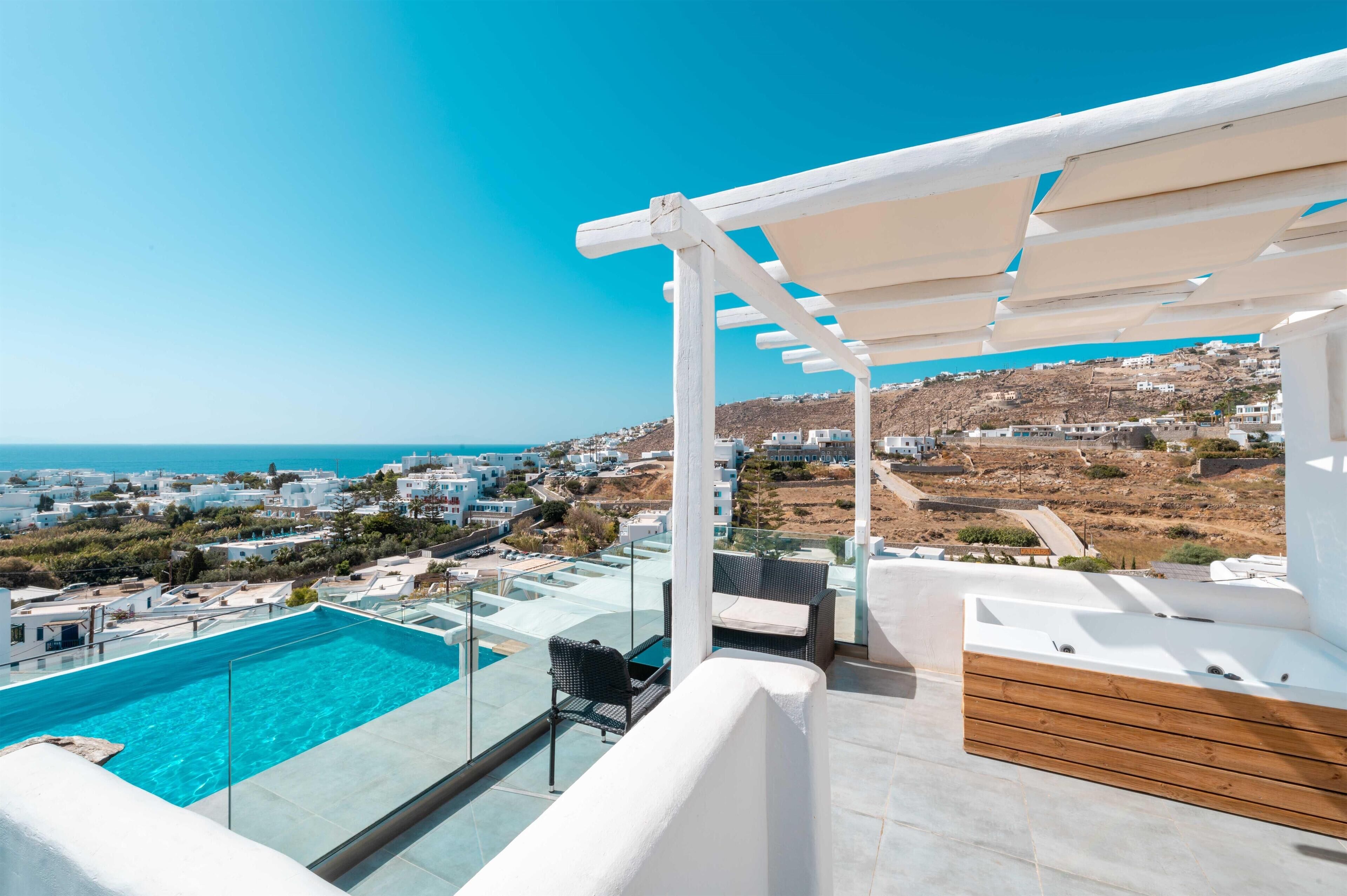 A rooftop terrace with a swimming pool, outdoor seating, and a view of the coastline.